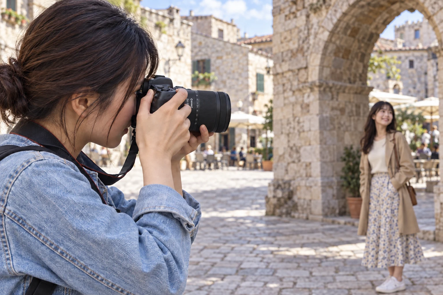 石のアーチ横の同行者へRF24-105mm付きカメラを向ける女性