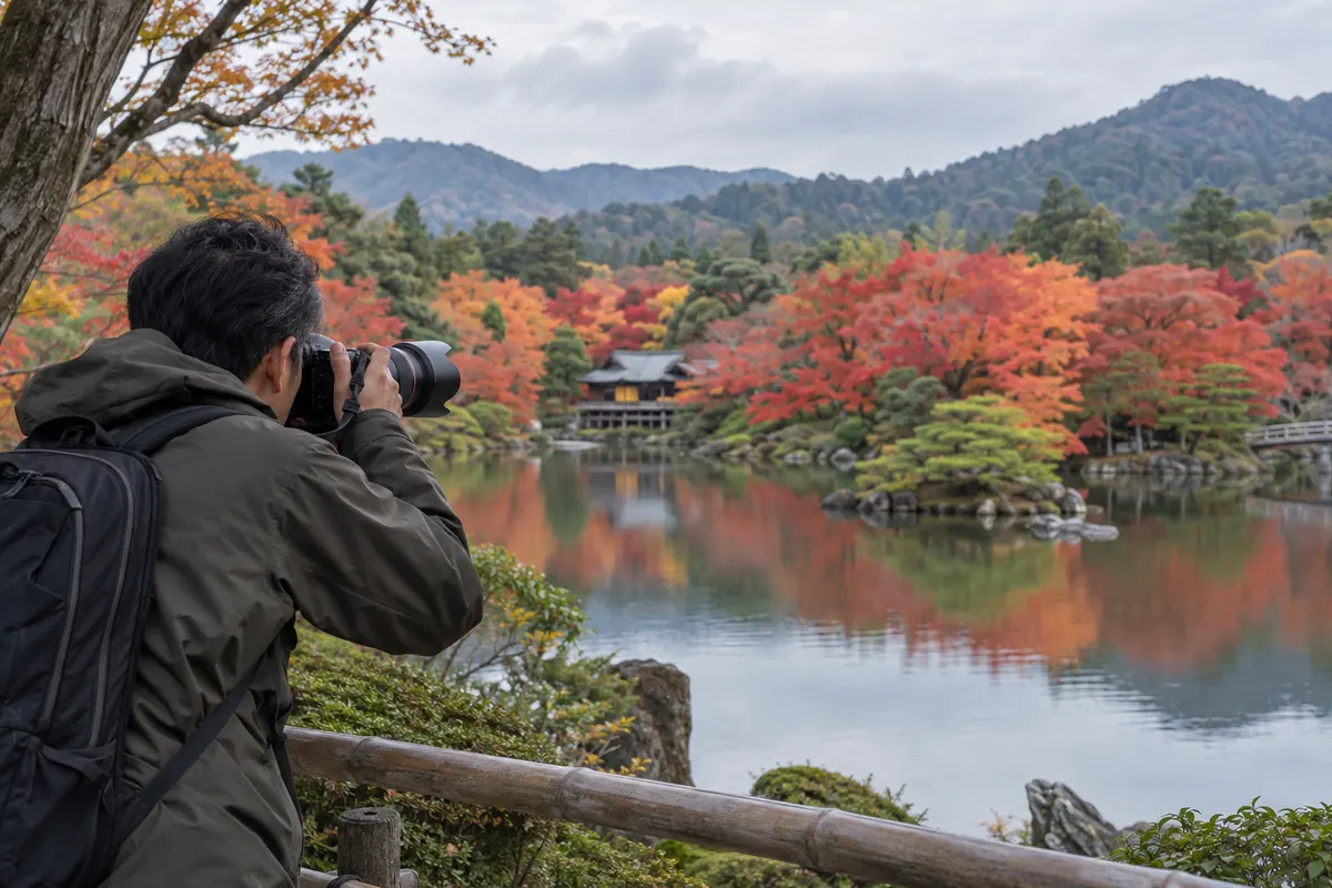 池の対岸の紅葉へ望遠レンズを向け、写す範囲を絞る撮影者