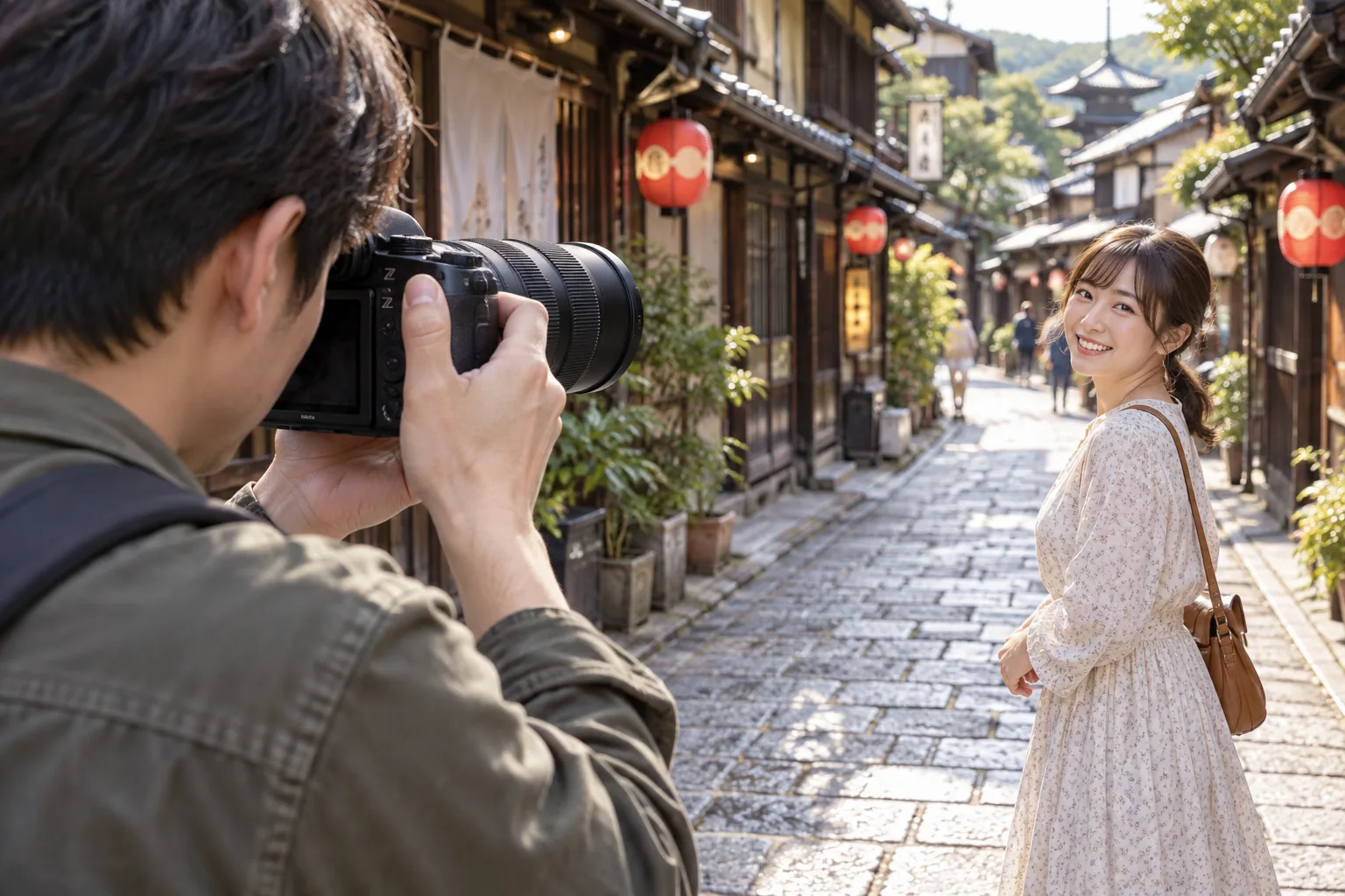 旅先の街路で両手で構えたカメラを同行者へ向け、ランタンの下で人物を撮る場面