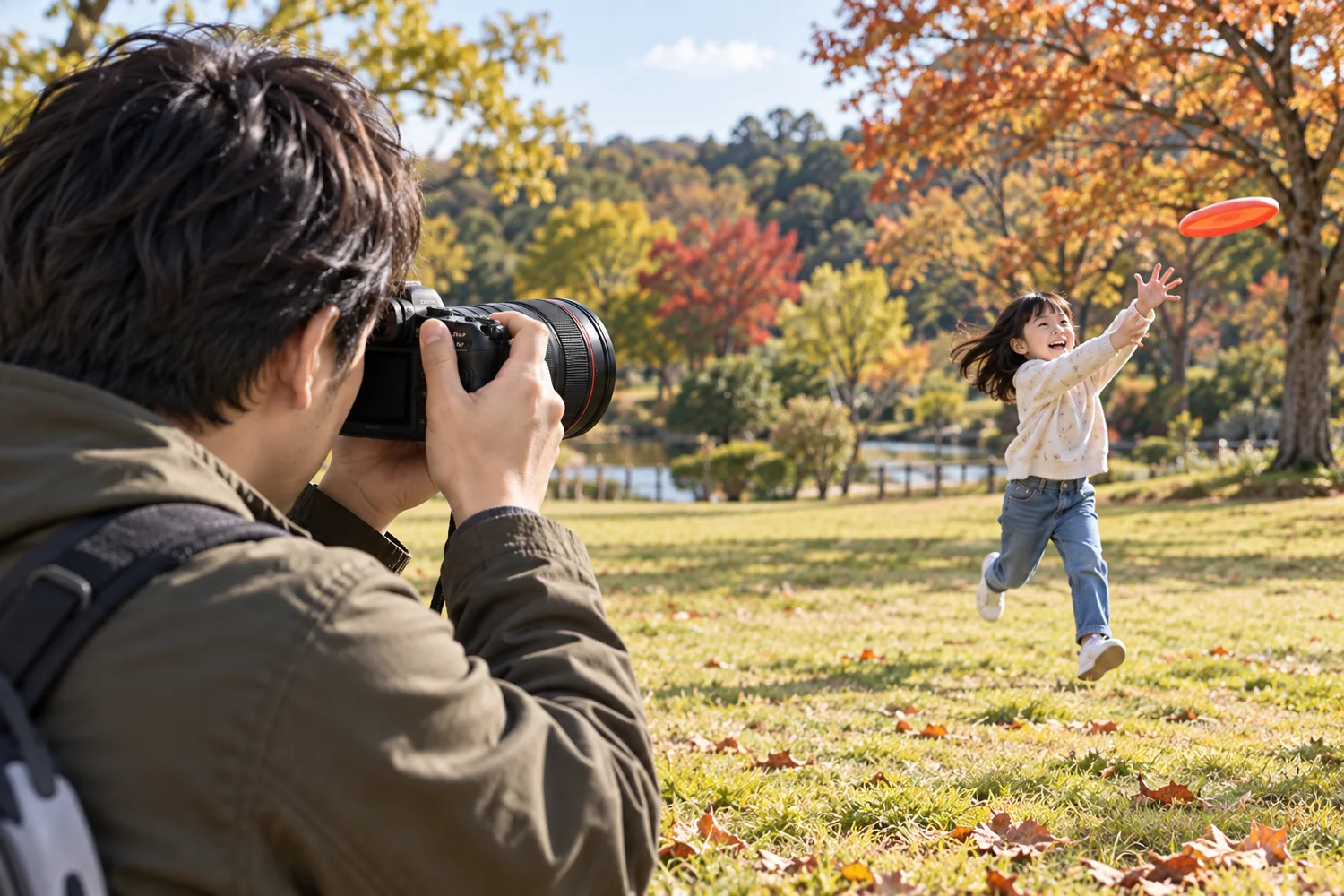 EOS R6 Mark IIとRF24–105mm F4 Lを構える親が、公園でディスクを追って跳ぶ子どもへレンズを向ける場面