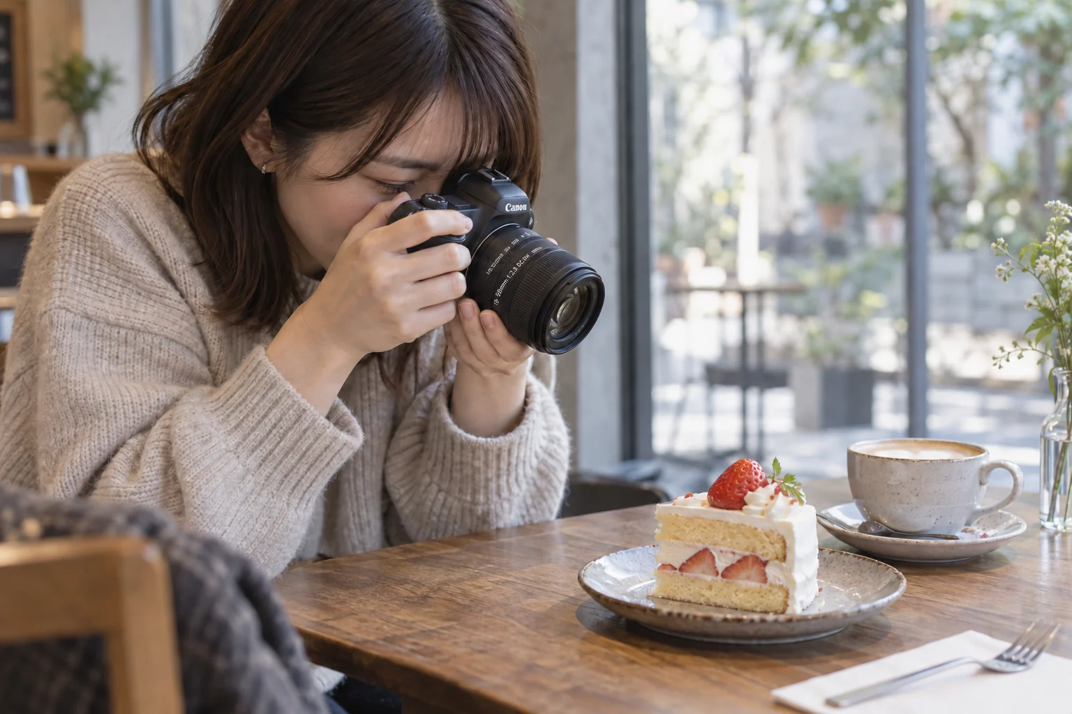 カフェで小さな標準ズーム付きのカメラをケーキへ向ける女性