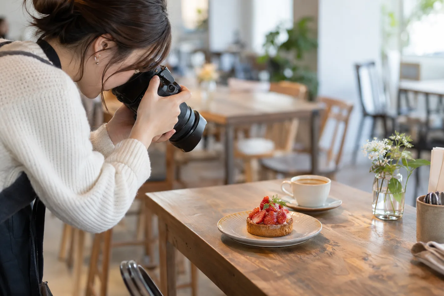 カフェのタルトに標準ズームを近づけて撮る女性