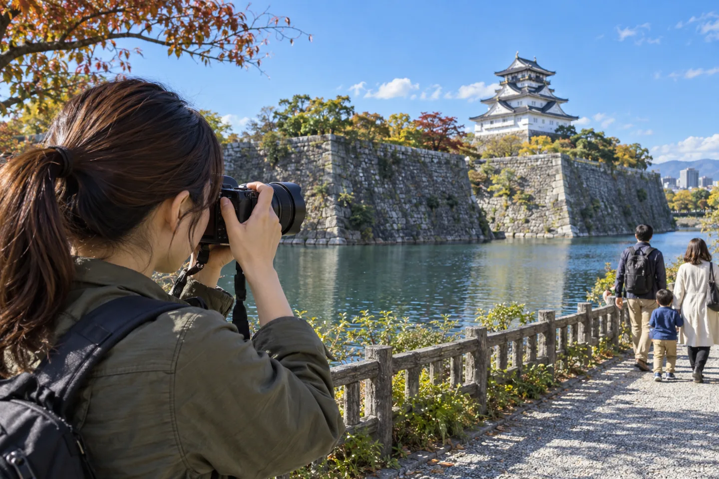 堀の向こうの城へ標準ズームを向ける女性