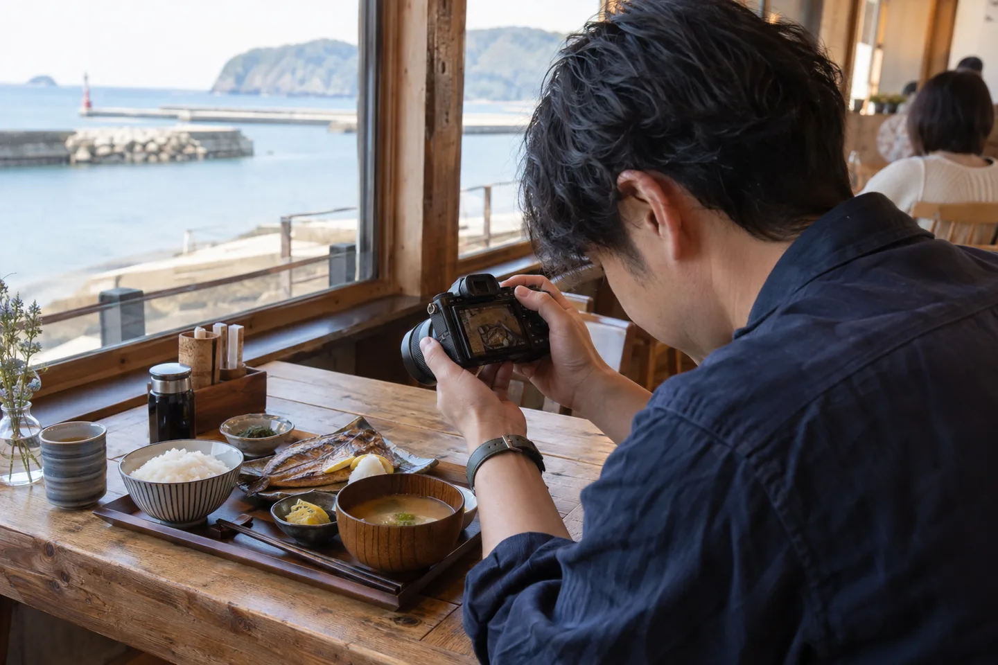旅先の焼き魚定食に小さな標準ズームを向ける男性