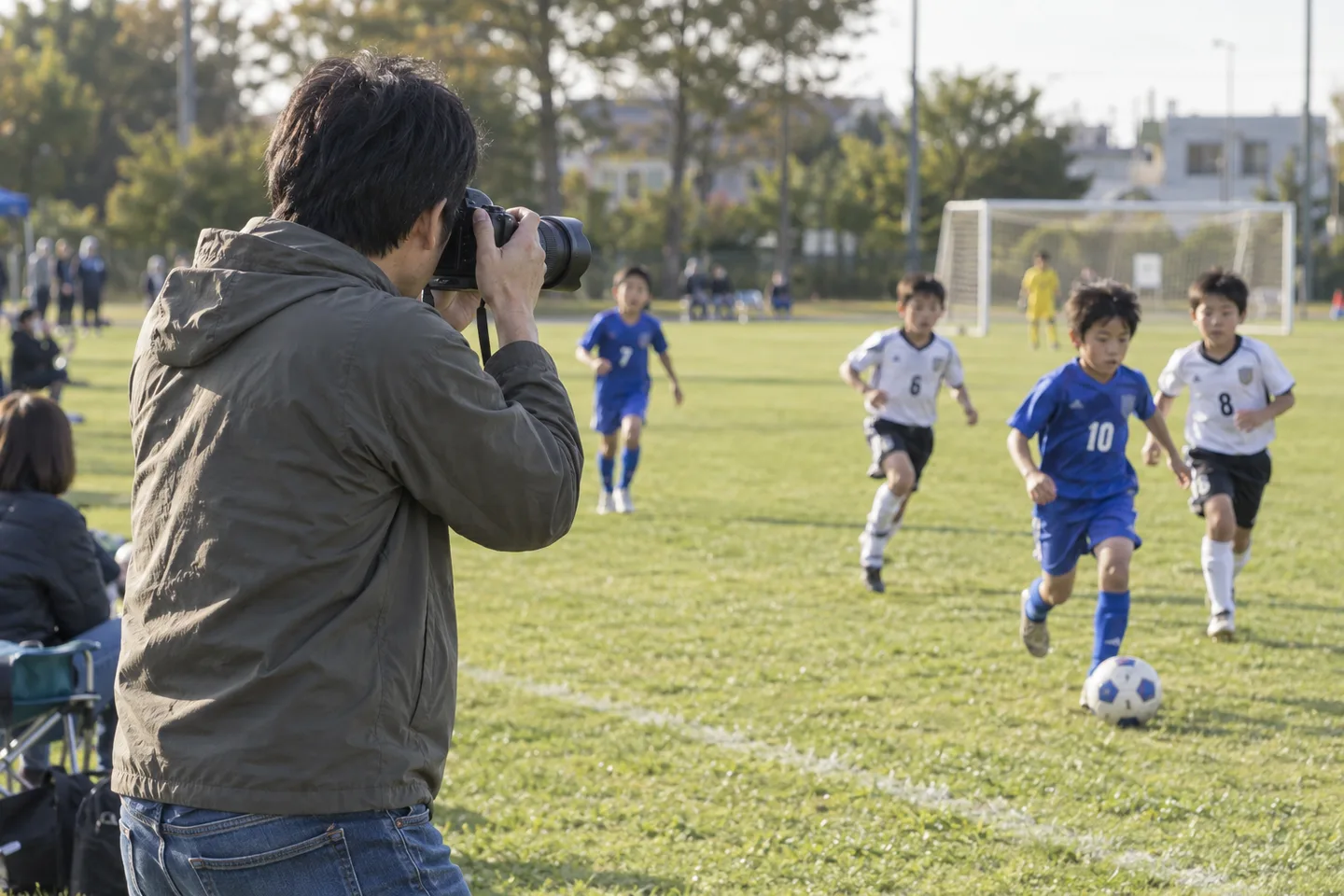 サッカーをする子どもへ黒い望遠ズームを向ける父親