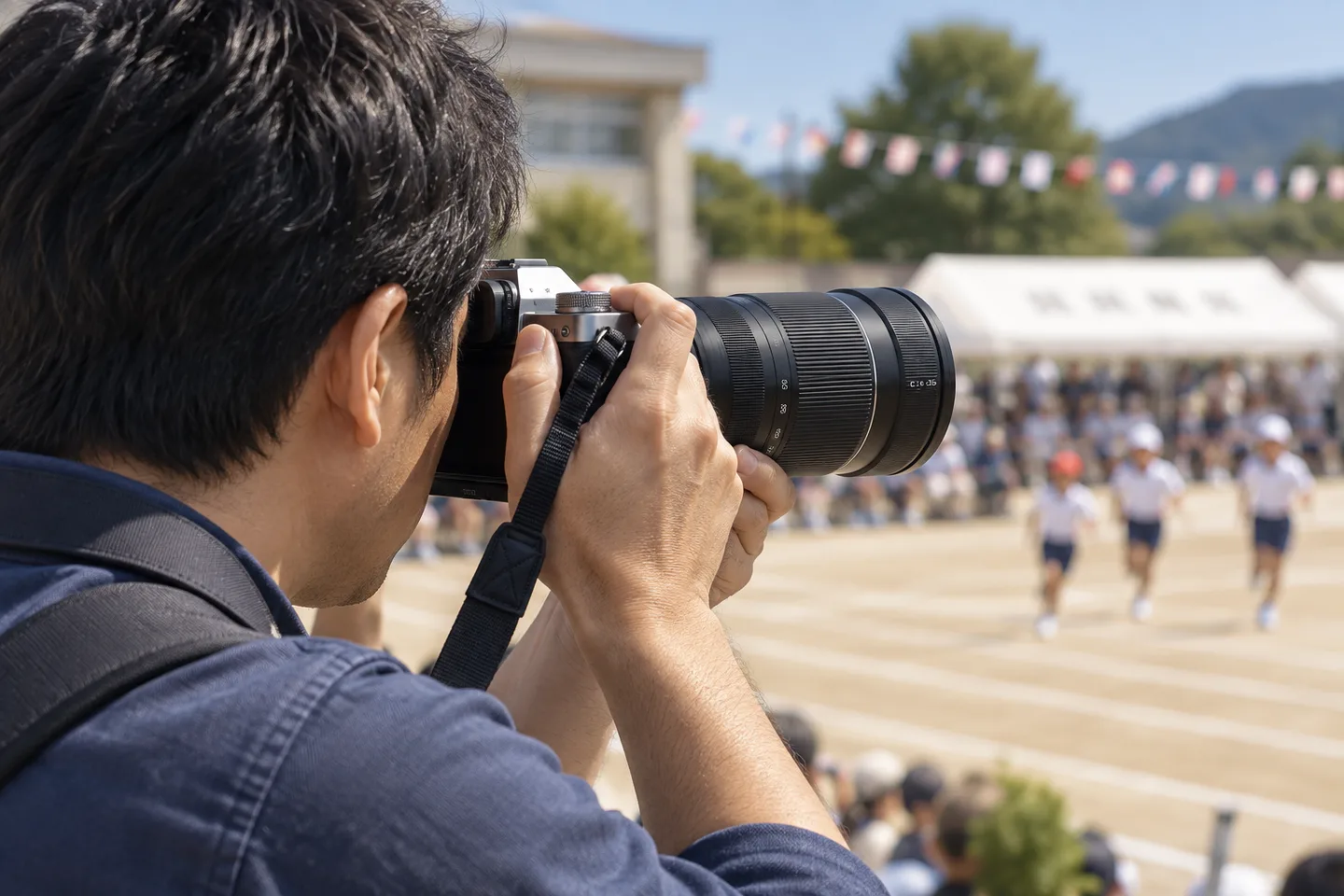 運動会でXC50-230mmを付けたカメラを構え、遠くの子どもを撮る場面