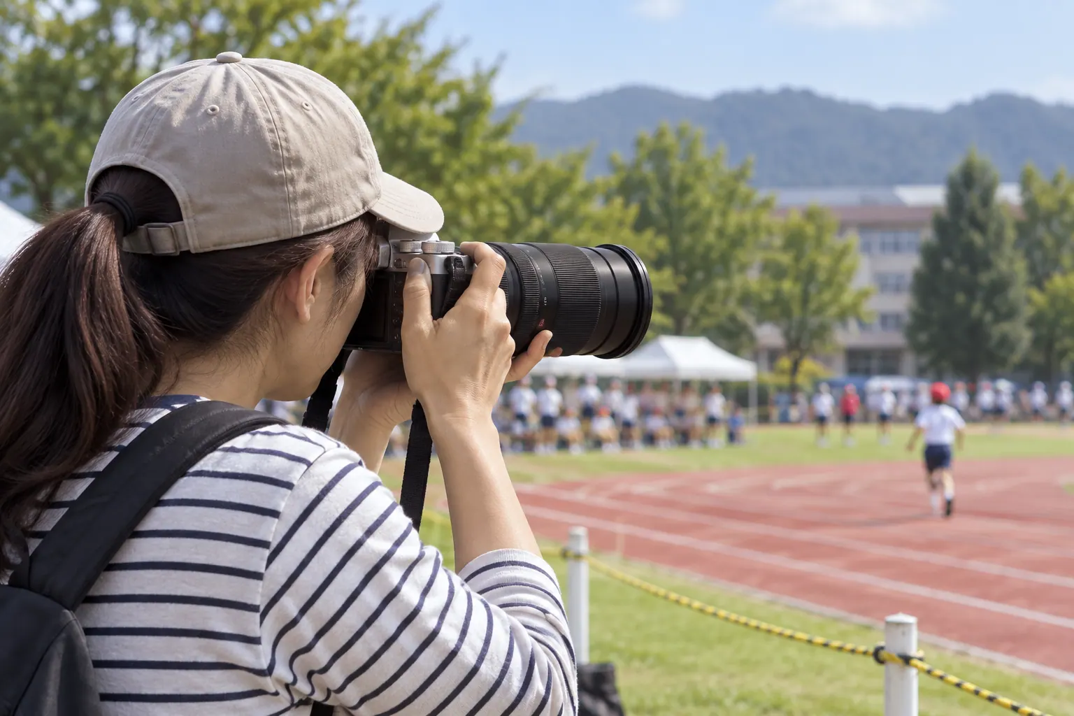 運動会で望遠ズームを使って遠くの子どもを撮る場面
